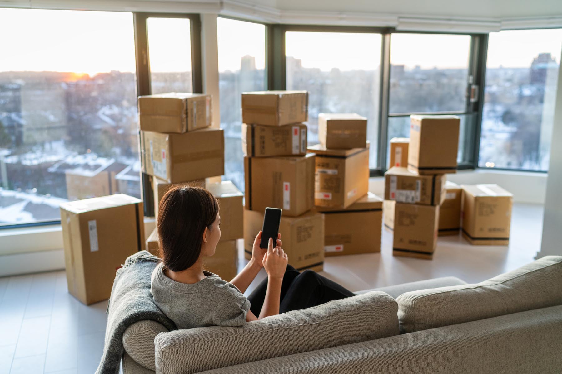 Woman searching for apartment movers with her apartment packed in boxes