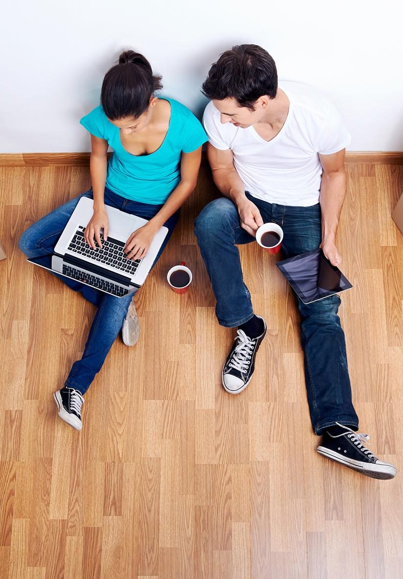 overhead view of couple sitting on floor together using computer wireless internet while moving into new home