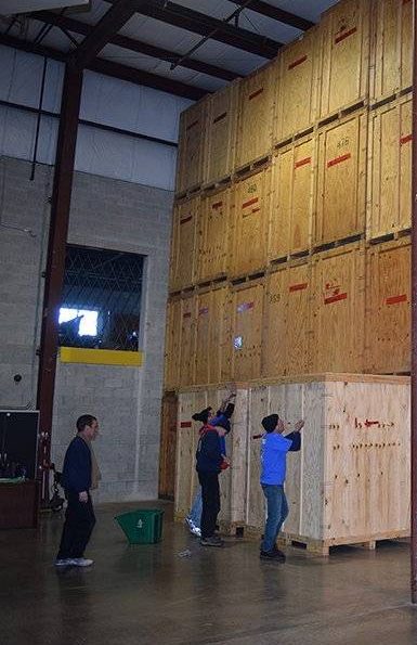 Movers pushing wooden vaults in storage warehouse